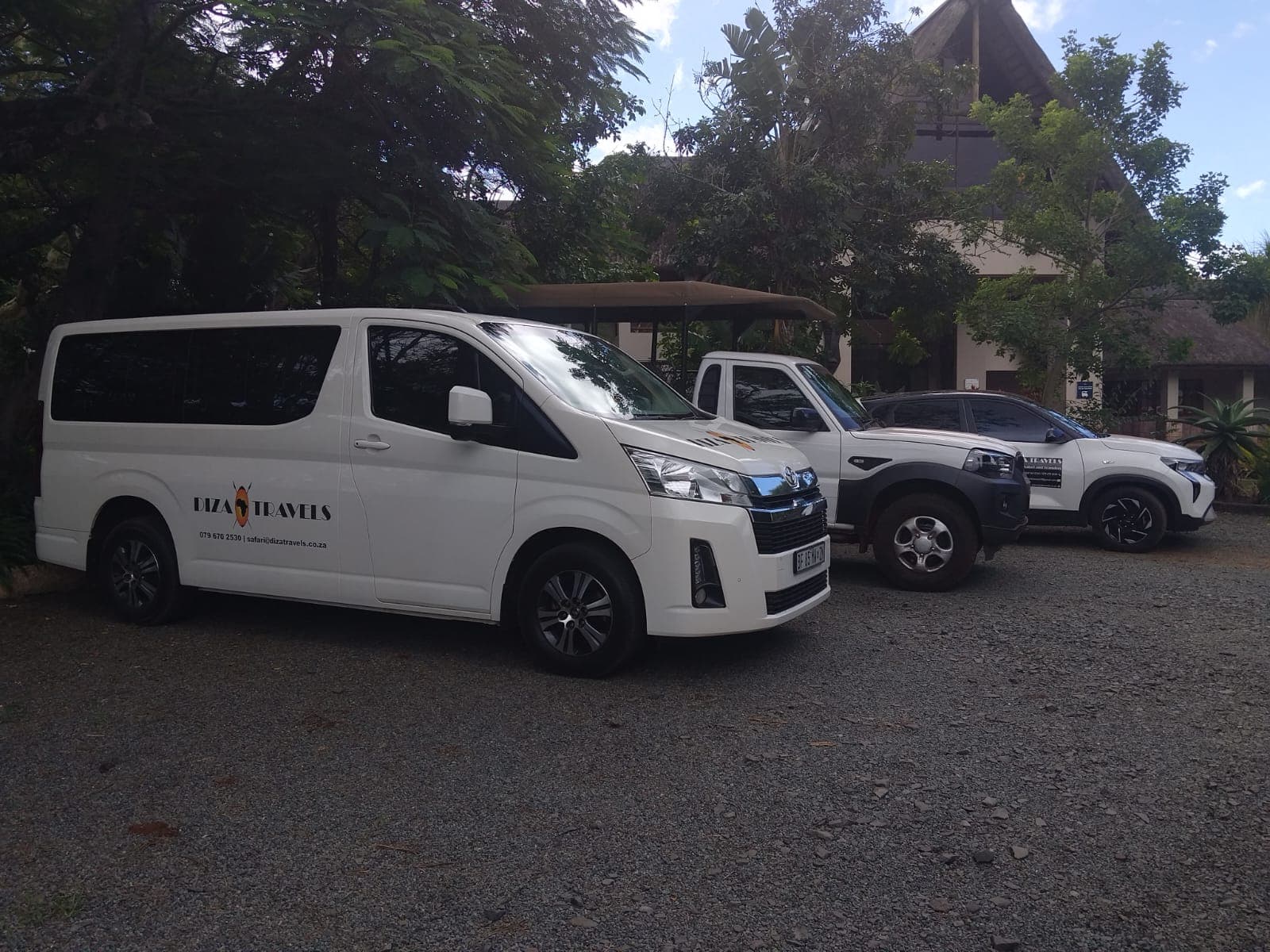 DIZA TRAVELS branded shuttle and safari vehicle fleet parked at a lodge in Hluhluwe